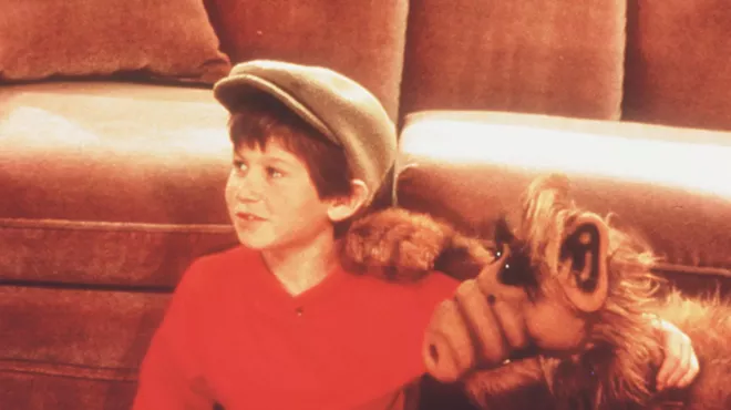 A young boy with an alien puppet.