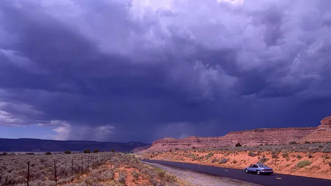 a rural southwestern road with gray clouds above