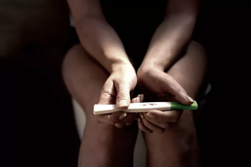 Image: a woman's hands holding a pregnancy test