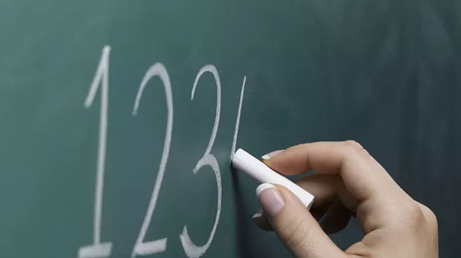 a hand writing 1-2-3-4 on a chalkboard