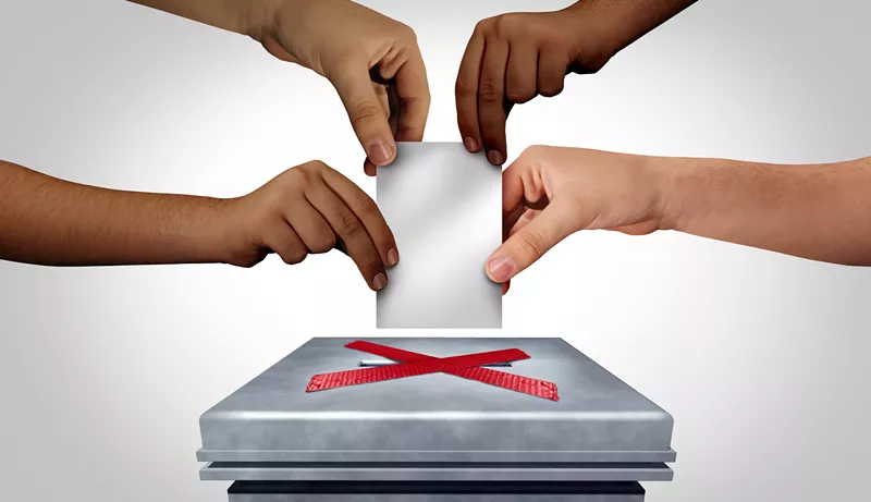 Image: four hands trying to put a piece of paper through a slot that is blocked off with an x