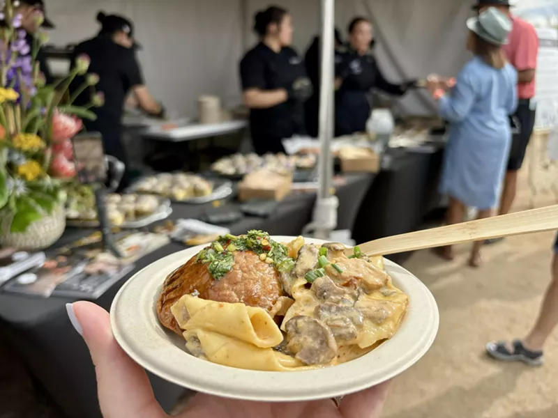 Image: Plate of pasta with tent in the background.