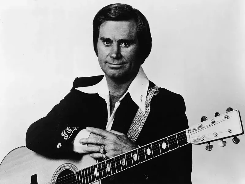 Image: Promotional studio portrait of American country singer and songwriter George Jones with an acoustic guitar, circa 1970.