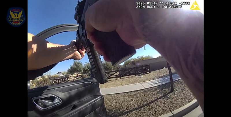 Image: body-cam footage of hands holding a rifle out an open car door
