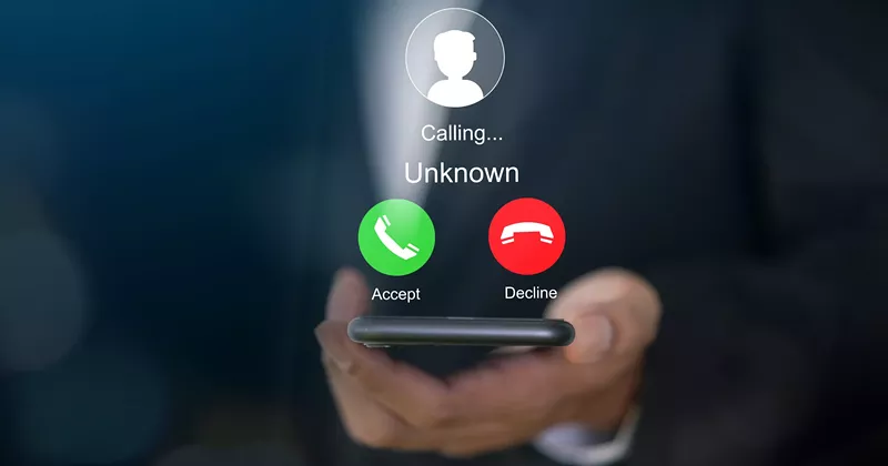 Image: a hand holding a phone that is getting a call from an unknown number
