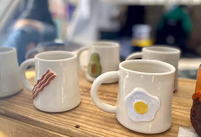 Image: Mugs by ceramic artist Colleen Colin say "wakey wakey, eggs, and bakey."