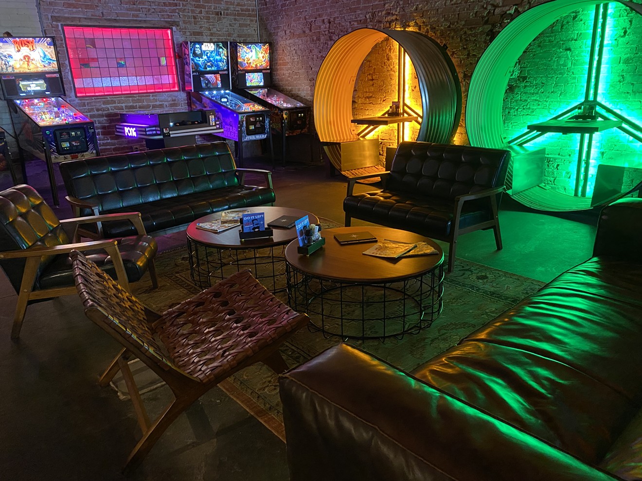 A lounge area with neon-lit corrugated metal pods and pinball machines set a vintage vibe.