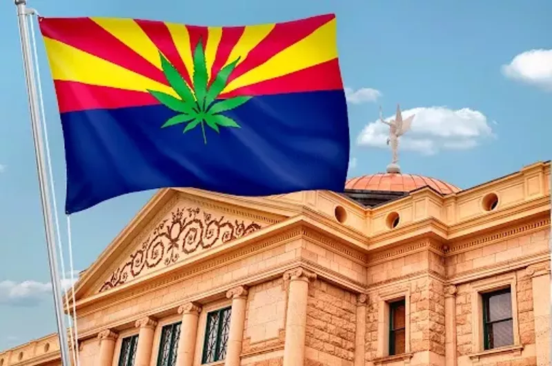 Image: an arizona flag with a marijuana leaf on it flies in front of the Arizona capitol