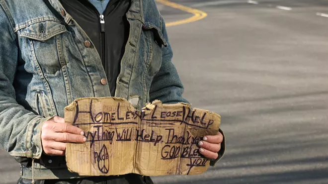 a man holding a cardboard sign near a road