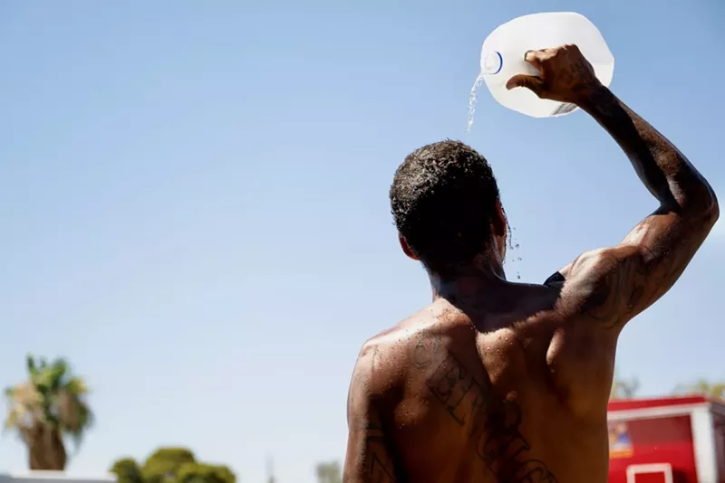 Image: Man pours water on his head.