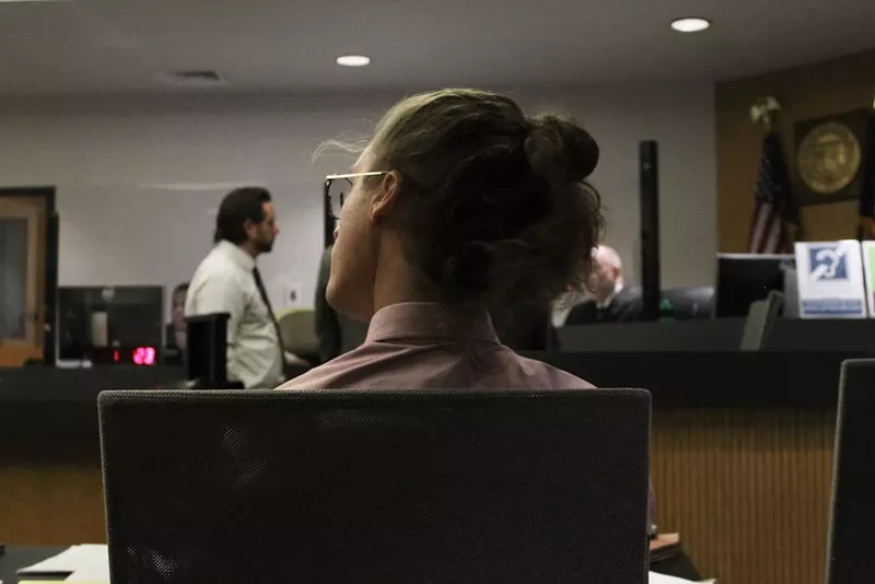 Image: A man, seen from behind, sits in a courtroom.