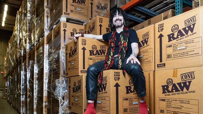 a man in a black shirt and red scarf sits on a pile of boxes