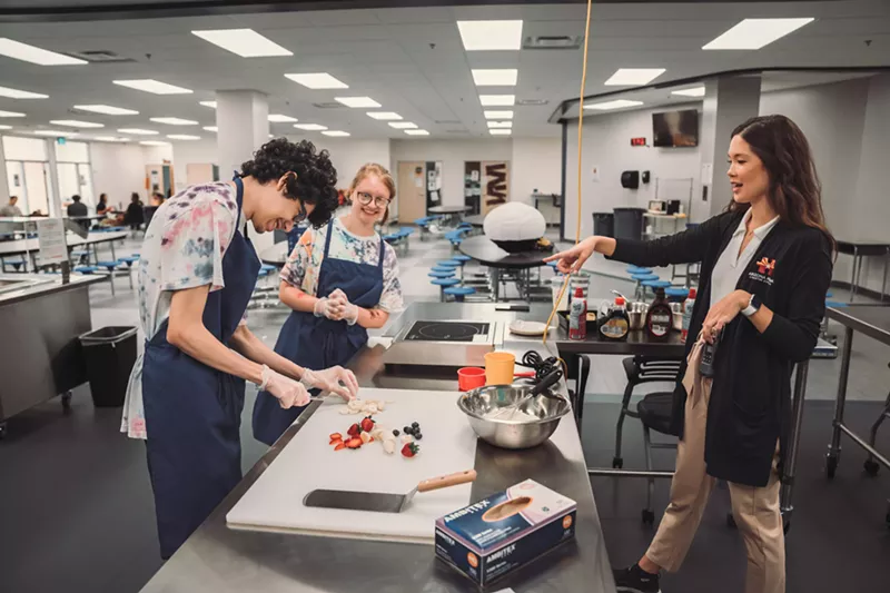 Image: Kati Sears, a culinary arts instructor at Arizona Autism Charter Schools, teaches students Christy and Brandon how to prepare toppings for pancakes.