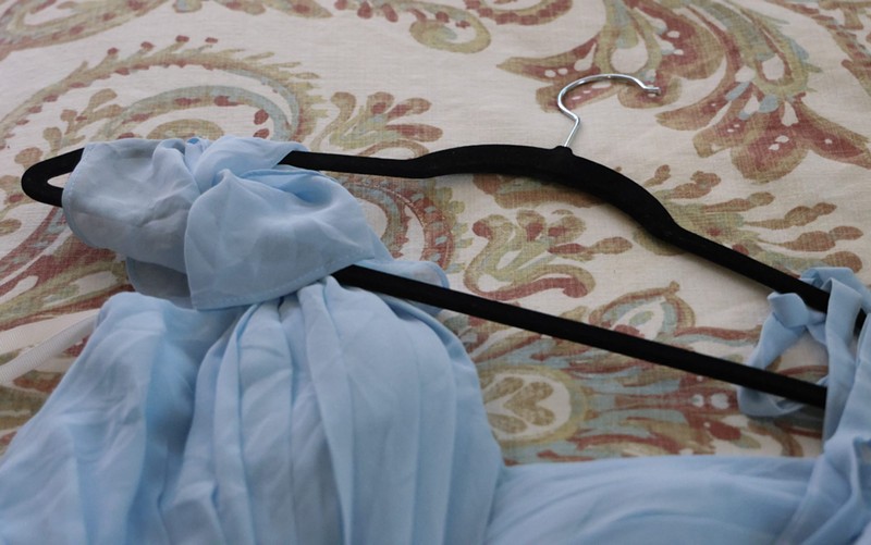 A blue dress is laid across a bed in the Gilbert casita where Reilly Oliphant runs Valley Girl Dresses.