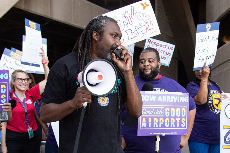 SEIU organizer Harris Harrigan leads a protest chant at Phoenix Sky Harbor International Airport on Wednesday.