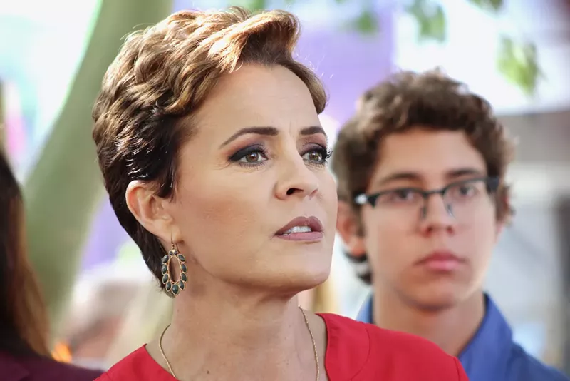 Image: Arizona political candidate Kari Lake, who wears a short haircut, speaks in front of a crowd.