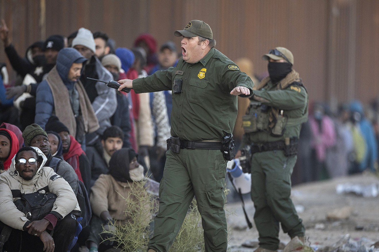 A U.S. Border Patrol agent shouts at immigrants who cut into a long line of people awaiting transport from the U.S.-Mexico border on Dec. 6 in Lukeville.
