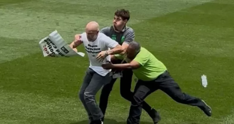 Image: a protester is tackled by two people on a soccer field