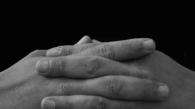 A black and white photo of folded hands.