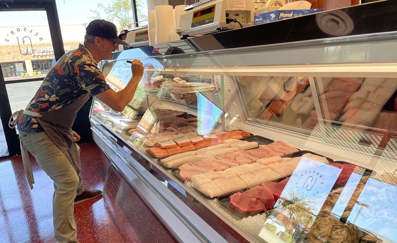 Nelson's Meat + Fish owner Chris Nelson writes pricing for seafood on the case before the shop opened its doors to customers on Tuesday.