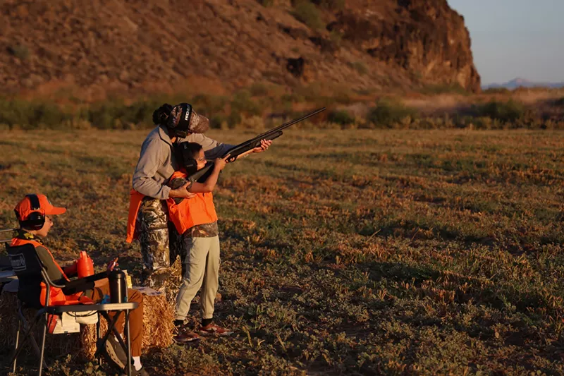 Image: Andrea Laughlin helps son Arrow, 9, aim his shotgun at the Dove Hunting Made Simple event on Sept. 7 in Buckeye.