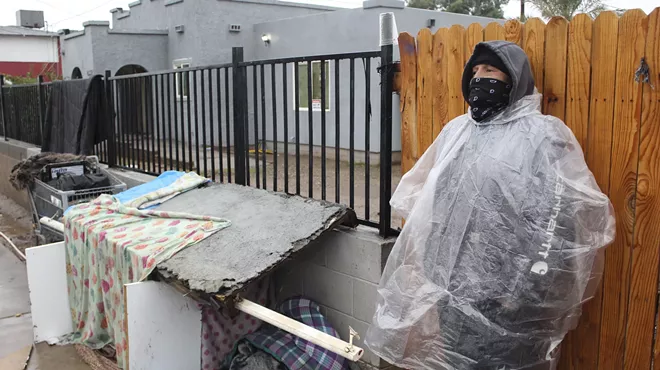 A man in a rain poncho stands on a street.