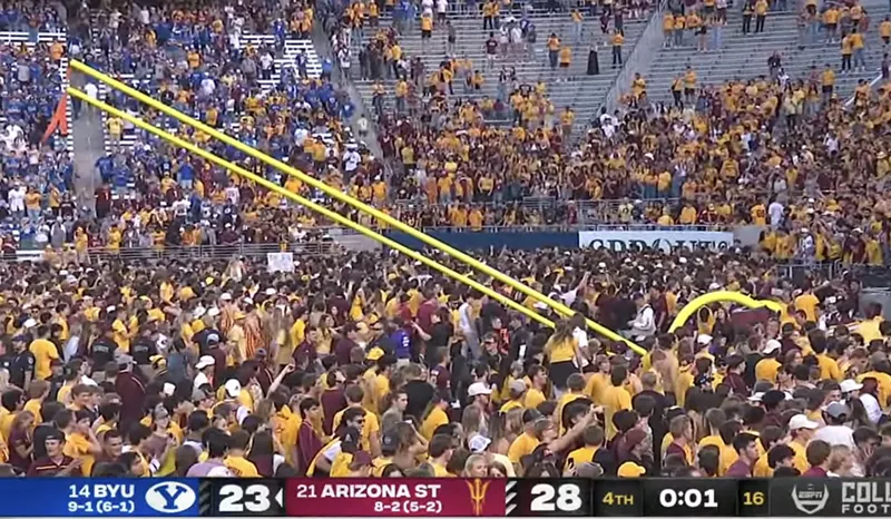 Image: a screenshot of a football game showing fans toppling the goalpost with one second still on the game clock
