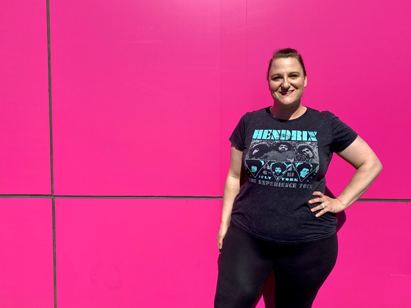 Amanda Hepler poses in front of the pink wall outside Otro Cafecito.