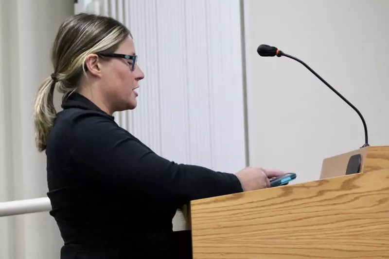 Image: a woman speaks into a microphone at a podium