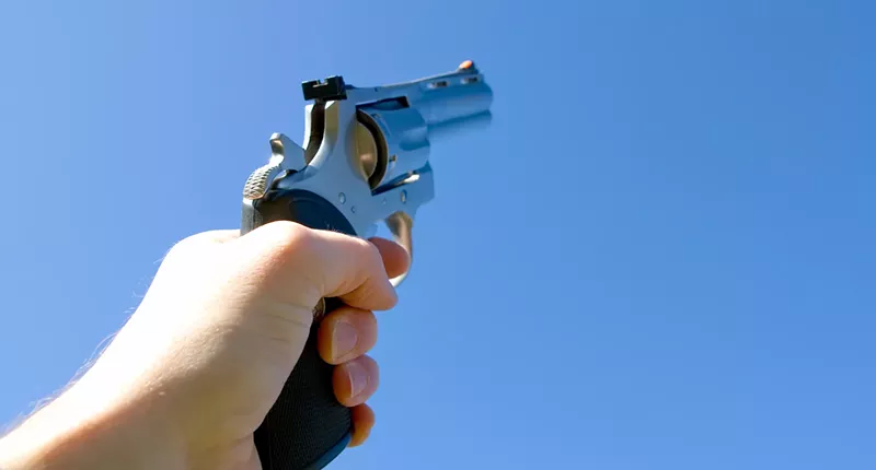 Image: a handgun pointed at the sky