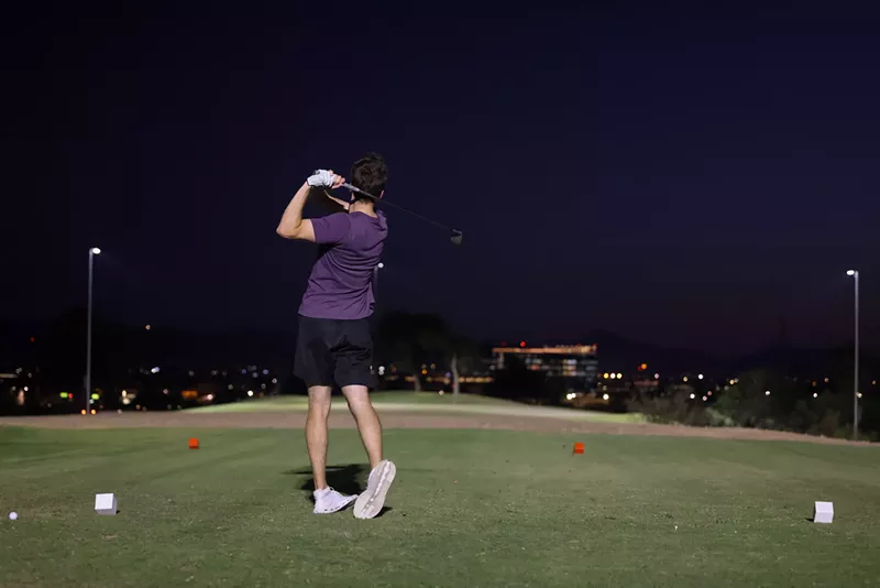 Image: A person plays golf at night.
