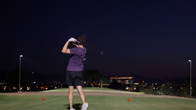 A person plays golf at night.