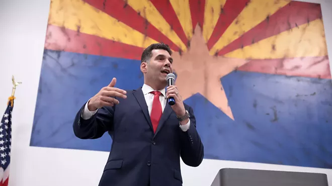 rodney glassman speaks in front of an arizona flag background