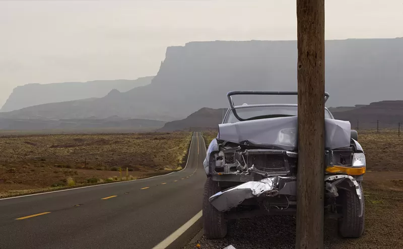 Image: a car crashed into a pole on a remote desert road