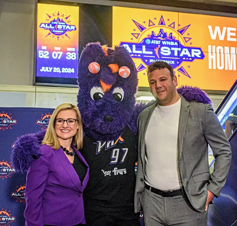 Image: A woman and a man pose for a photo with a person in a purple dragon costume.
