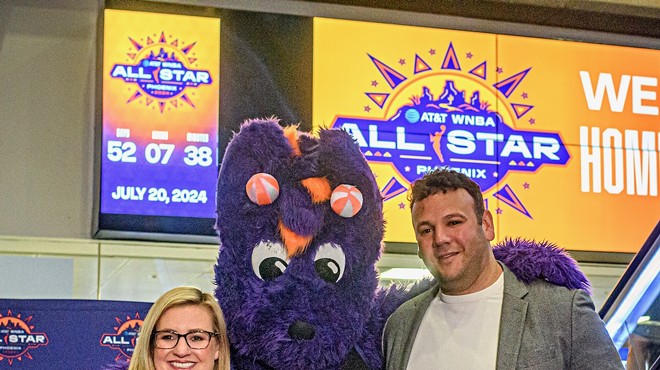 A woman and a man pose for a photo with a person in a purple dragon costume.