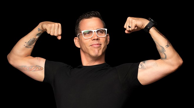 A man on a black background flexing his muscles.