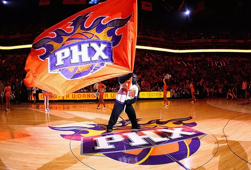 Image: the suns gorilla mascot waving a suns flag on the court