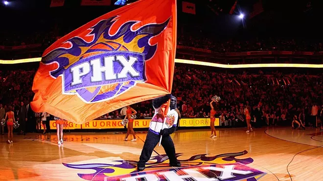 the suns gorilla mascot waving a suns flag on the court