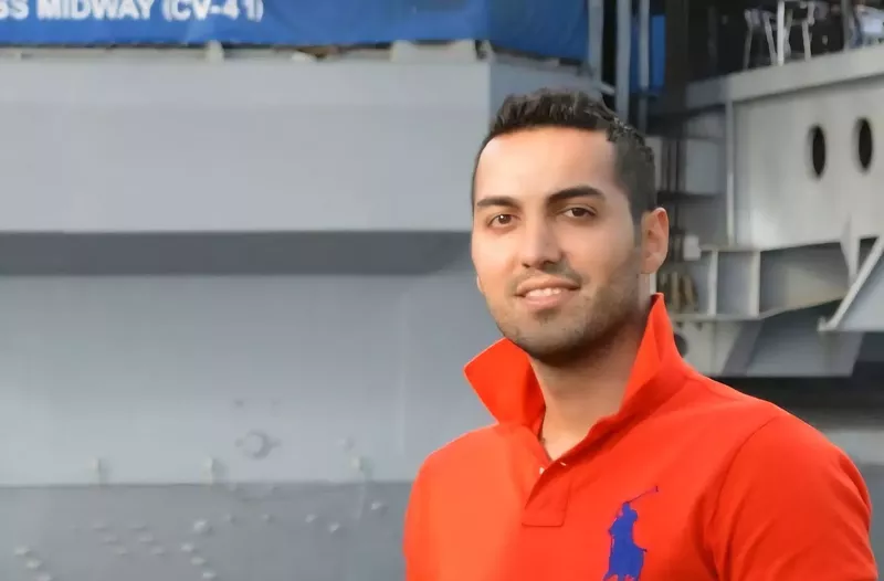 Image: a man in an orange polo shirt with the collar flipped up
