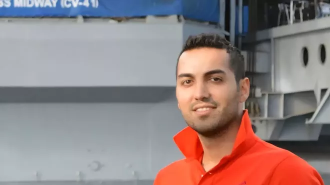 a man in an orange polo shirt with the collar flipped up