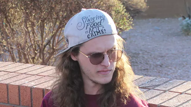 a young man in a backward hat that says "sharing food is not a crime"