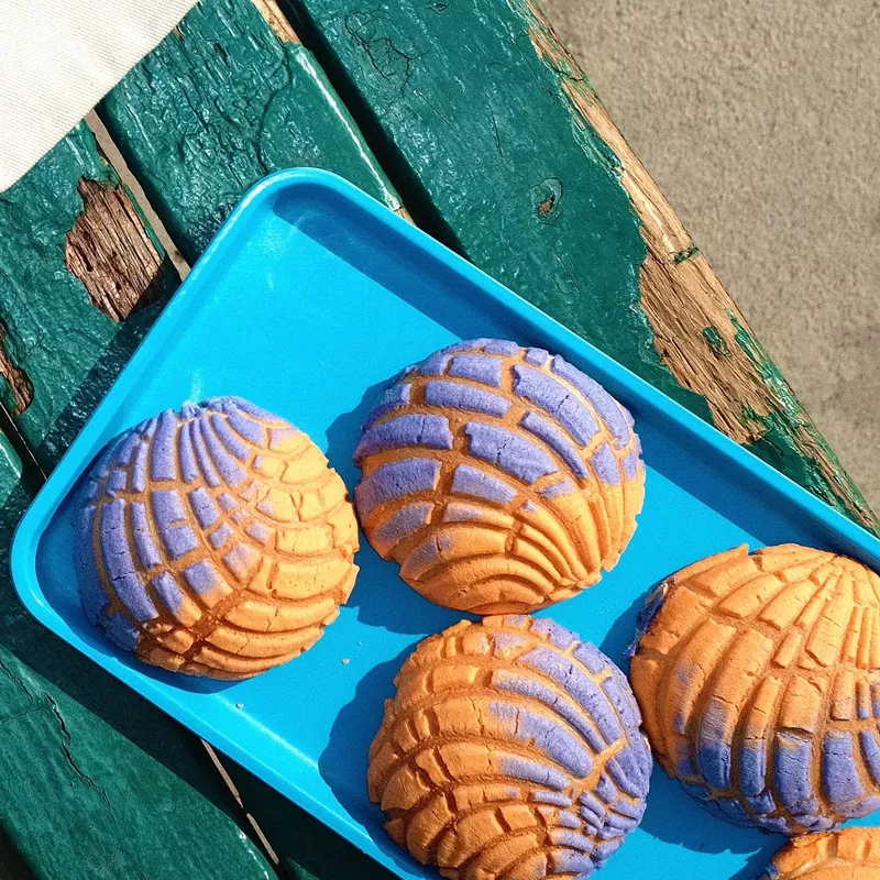 Image: Tray of purple and orange conchas.