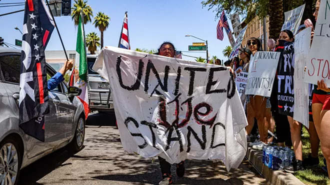 a woman walks down the street holding a banner that says "united we stand"