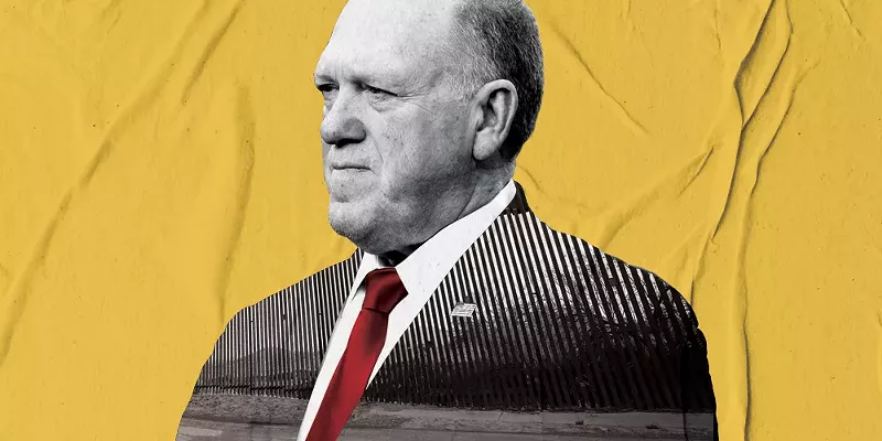 Image: tom homan in a suit from the chest up, but the inside of the suit is a picture of a border wall