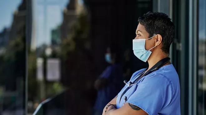 a health worker in a mask stares into the distance