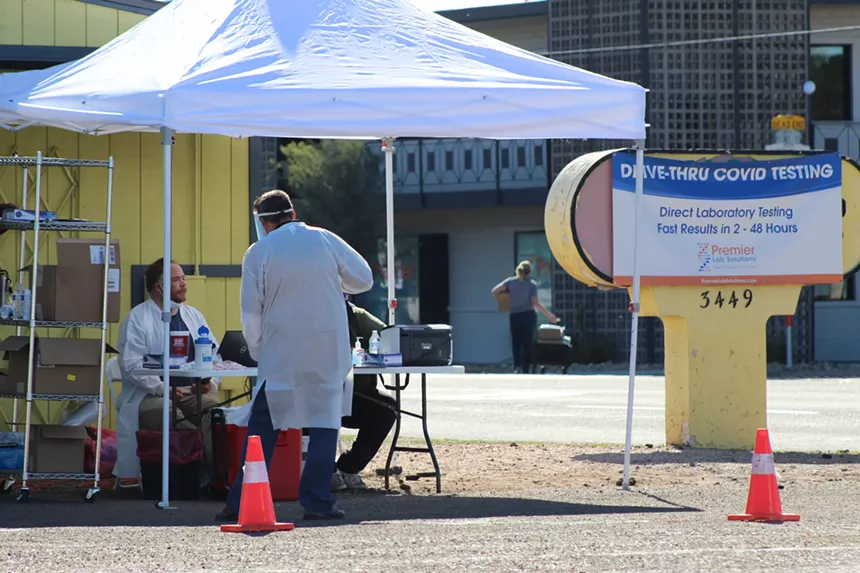 Medical staff chat at Premier Lab Solutions' drive-thru COVID-19 testing clinic at 16th Street and Mitchell Drive. Visible from the busy roadway is a sign boasting results in as few as two hours – but some patients report waiting weeks or months for answers. - ELIAS WEISS