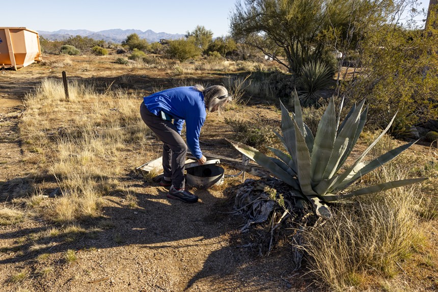 John Hornewer lifts the mouth of a cistern next to an agave plant in the Rio Verde Foothills. - ZEE PERALTA