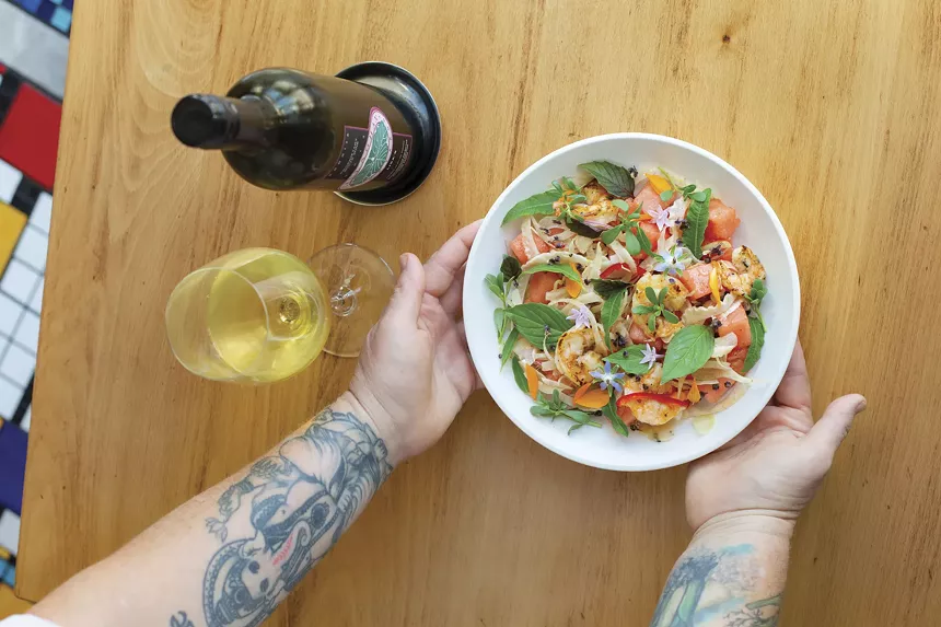 Chef puts plate of food on table.