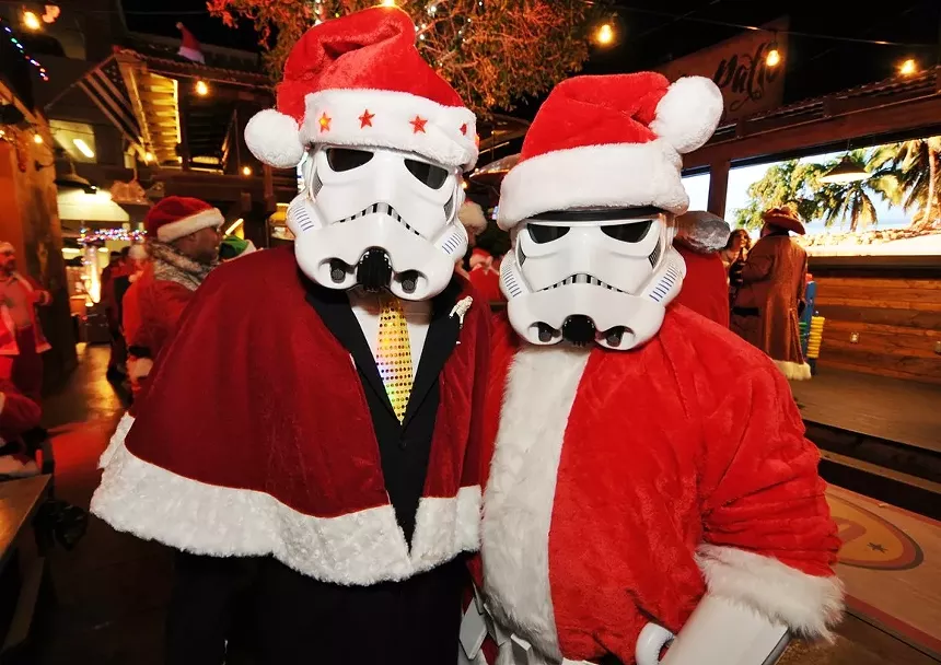 Two people wearing Santa suits and Star Wars masks